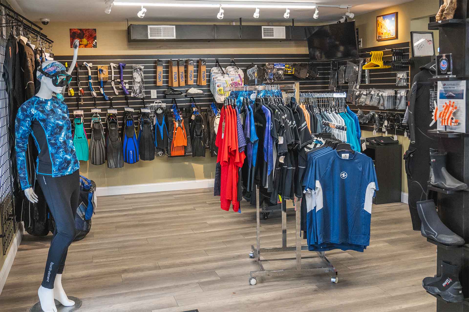 Scuba gear retail display featuring wetsuits drysuits rash guards and fins in organized product sections