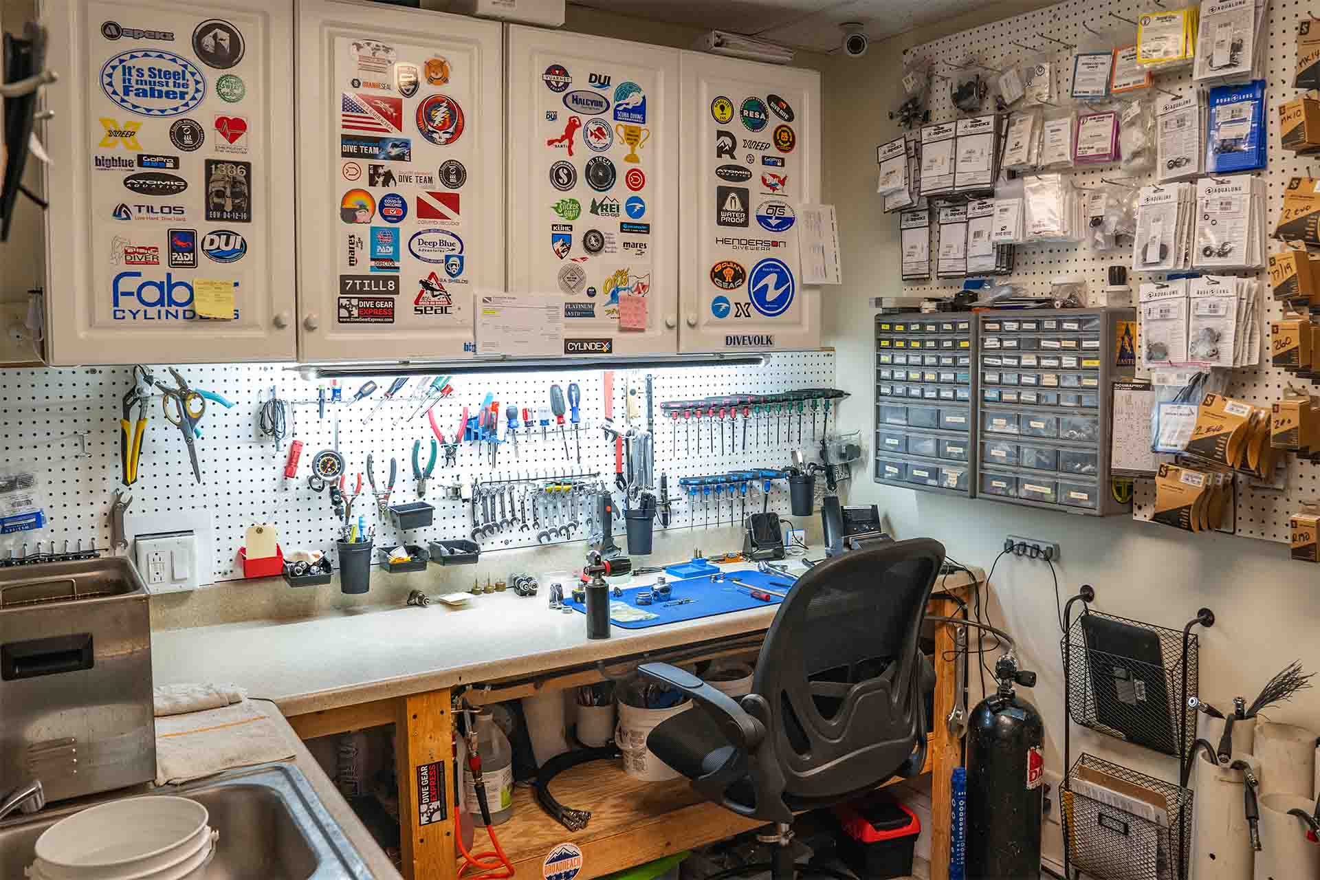 Professional service workbench with precision tools wrenches organized parts storage and dive stickers at Columbus Scuba