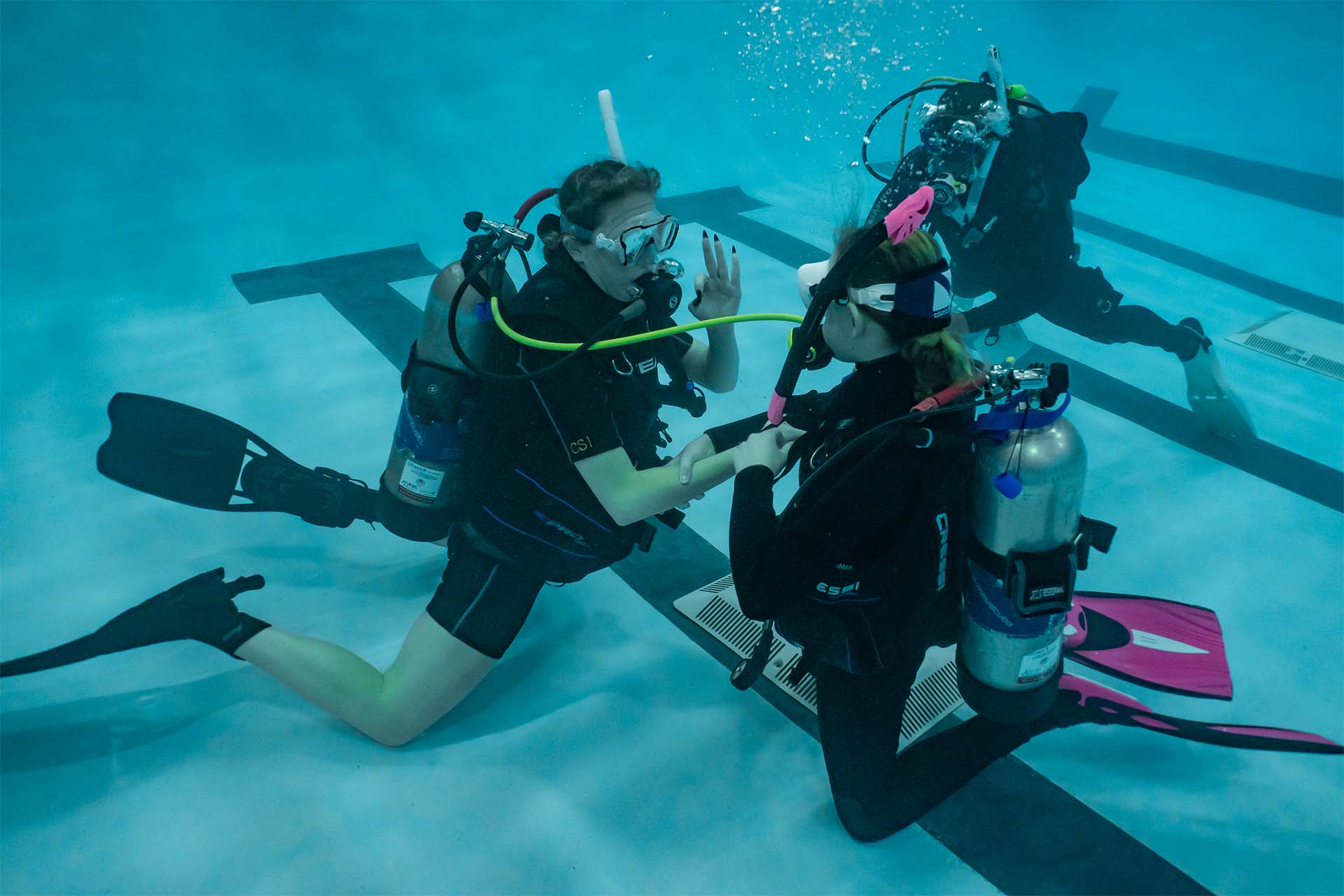 PADI Divemaster candidate conducting underwater skill demonstration with a student diver during pool training session — Columbus Scuba Columbus Ohio